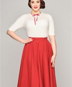 Femme souriante portant une jupe swing rouge et un haut à manches courtes blanc.