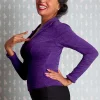Femme souriante en pull violet, main sur la poitrine, style vintage.