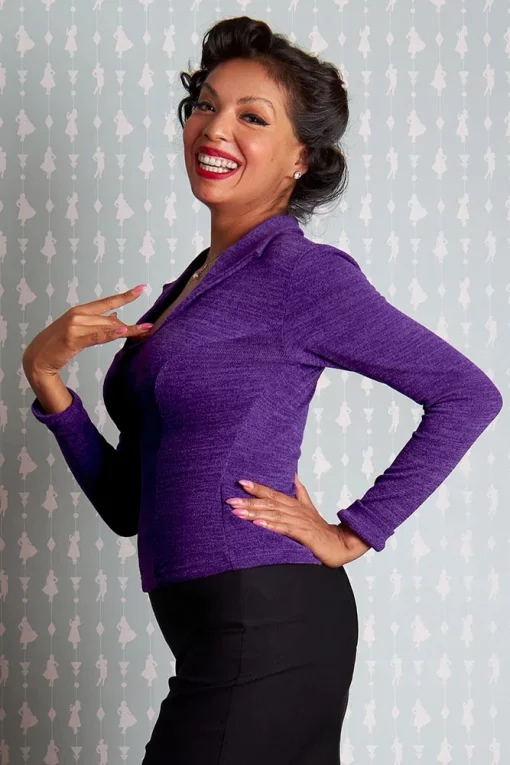 Femme souriante en pull violet, main sur la poitrine, style vintage.