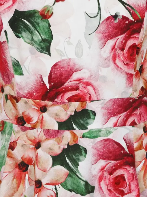 Zoom sur le tissu de la robe swing montrant des roses roses délicates et des feuilles vertes.