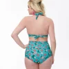 Femme blonde avec main sur la hanche affiche le Bas de maillot de bain bleu à fleurs style naïf, 50's, de dos Station Vintage