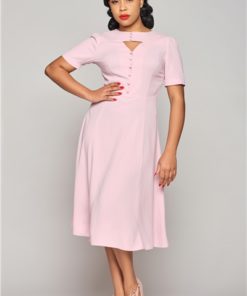 Femme avec la main sur la hanche pour présenter la robe évasée rose disponible chez Station Vintage